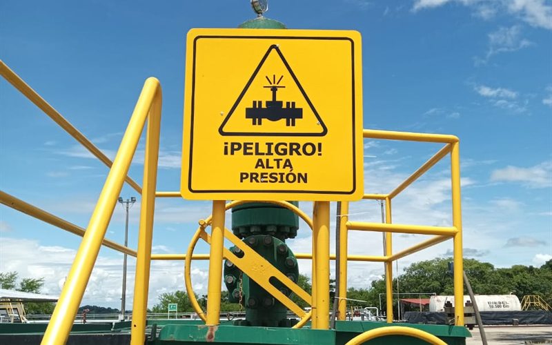 Yellow high-pressure danger sign installed above a valve at an industrial plant